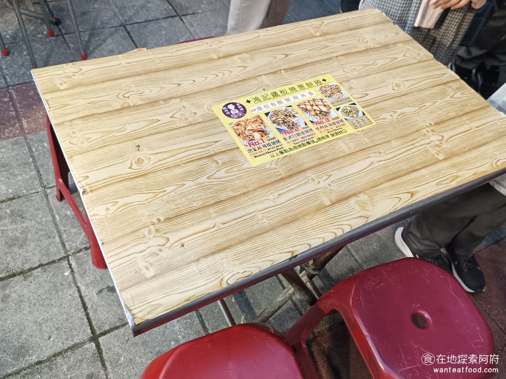 鴻記鐵板燒蔥餅捲 大同區美食 台灣小吃 店內座位幾乎都空蕩蕩的，許多位置閒置，營造出一種鬧中取靜、非常舒適的用餐環境 XD。不過，身後卻是一條長長的排隊人龍，大家都在等待購買劉家芋頭丸，因此我一直被眾多顧客注視著享用，讓我有一點不好意思 XD。 @在地老饕阿府